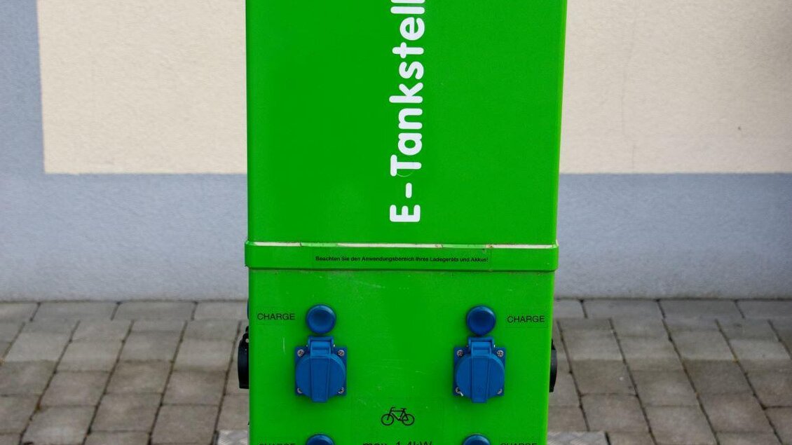 Eine grüne E-Tankstelle mit mehreren Ladeanschlüssen. Sie steht auf einem gepflasterten Boden und hat ein modernes Design. | © Kurkommission Bad Blumau