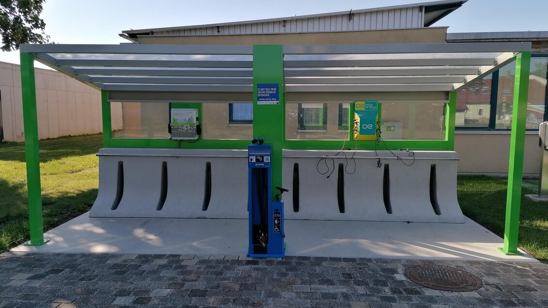 Eine moderne Waschstation für Autos mit einem blauen Bediengerät und grünen Akzenten. Die Station befindet sich unter einem überdachten Bereich auf einem gepflasterten Boden. | © Kurkommission Bad Blumau