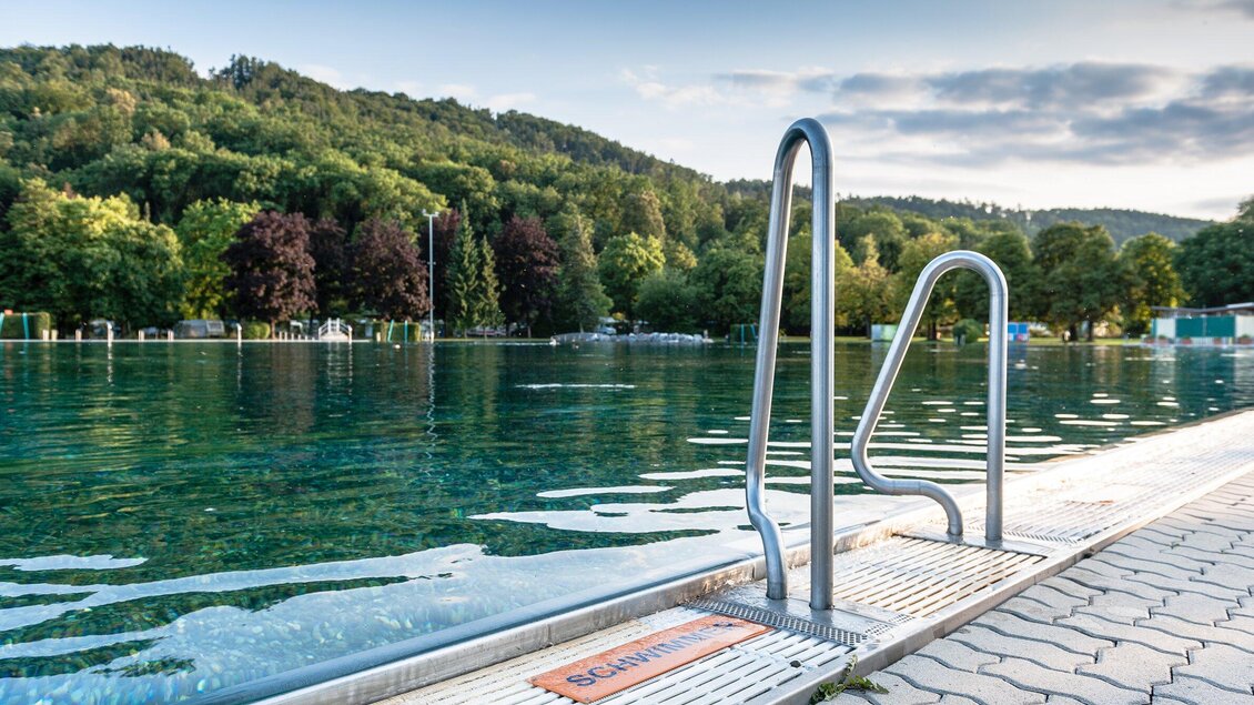 Blick auf das Naturbad Straßgang in Graz mit Wasserzugang und Waldkulisse | © Holding Graz - Joel Kernasenko
