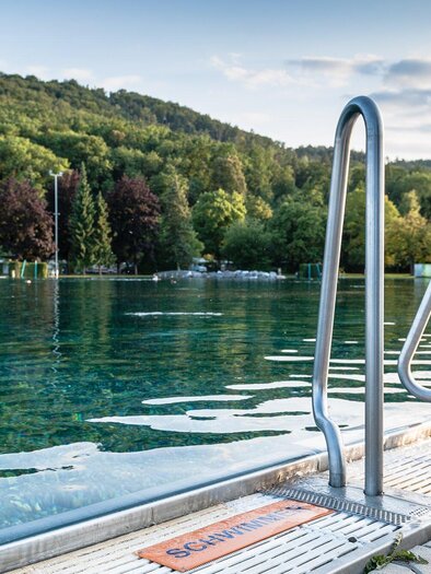 Blick auf das Naturbad Straßgang in Graz mit Wasserzugang und Waldkulisse | © Holding Graz - Joel Kernasenko