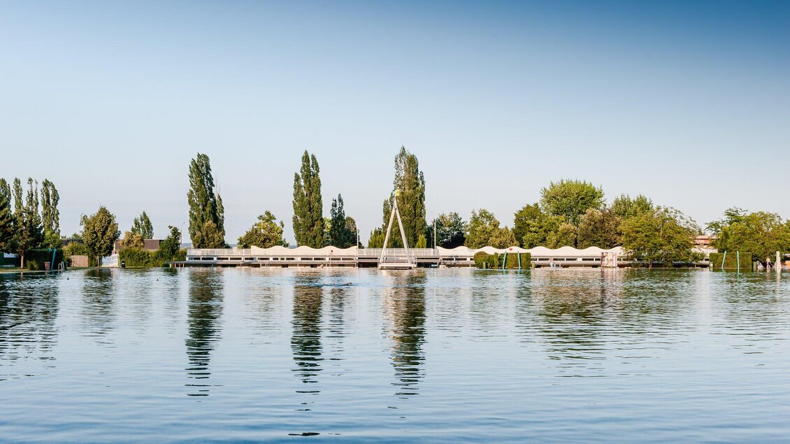 Weitblick über das Naturbad Straßgang in Graz mit Steg und Bäumen | © Holding Graz - Joel Kernasenko