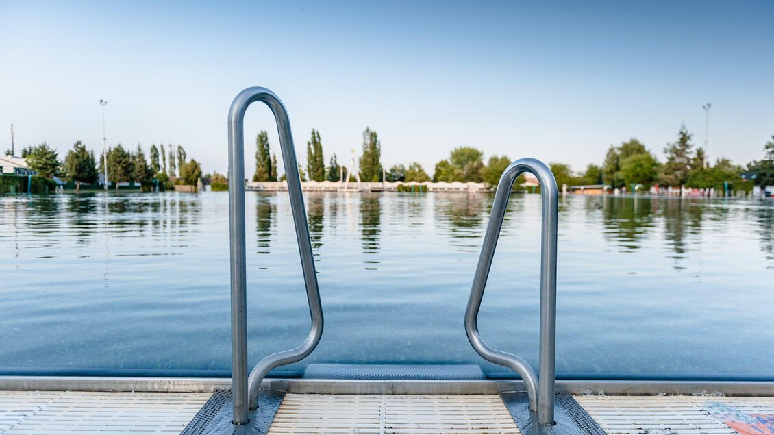 Blick auf Edelstahlleiter am Naturbad Straßgang in Graz mit ruhiger Wasserfläche | © Holding Graz - Joel Kernasenko