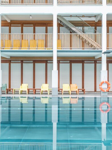 Interior view of the indoor swimming pool at Bad zur Sonne with colorful sun loungers in Graz | © Holding Graz - achtzigzehn