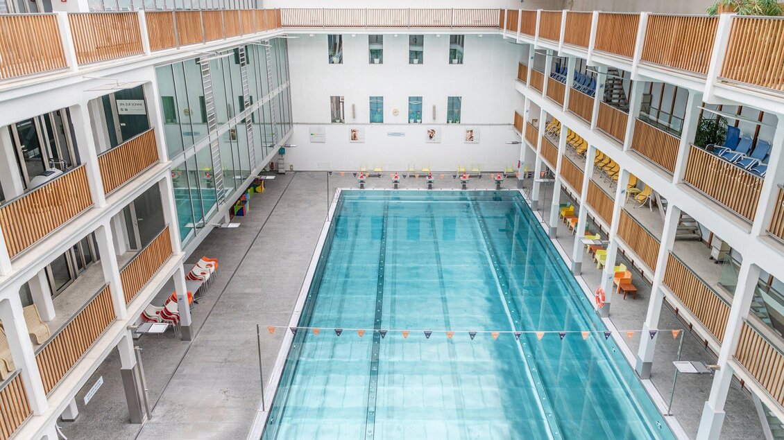 Blick von oben auf das große Hallenbecken im Bad zur Sonne in Graz mit Liegestühlen  | © Holding Graz - achtzigzehn