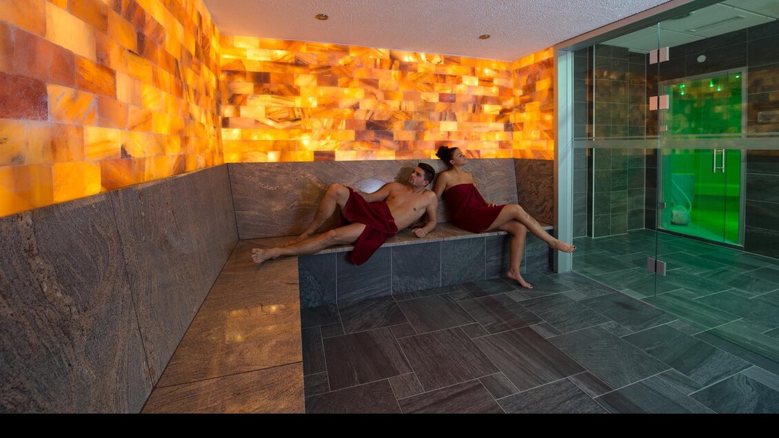 Ein entspannender Wellnessbereich mit sanftem Licht und gemütlichen Liegen. Zwei Personen genießen die Ruhe in einer modernen Umgebung. | © Stadtgemeinde Kapfenberg