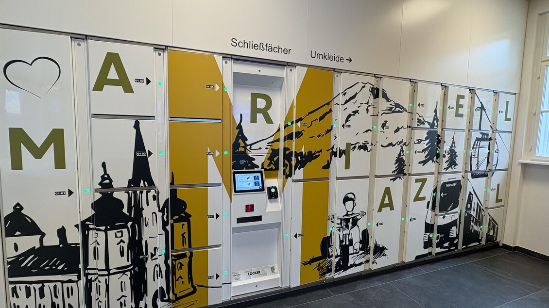 Ein modernes Schließfachsystem mit dekorativen Illustrationen von Bergen und Gebäuden. Es steht in einem hellen Innenraum und bietet einen einfachen Zugang zu persönlichen Aufbewahrungslösungen. | © TV Hochsteiermark