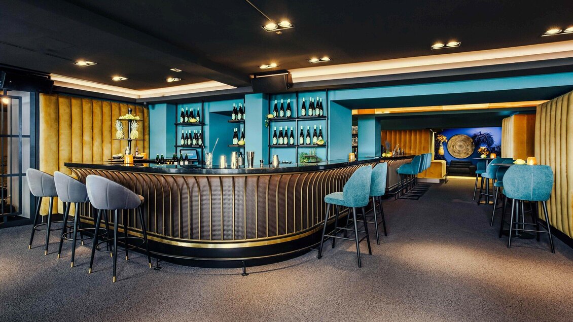 Eine stilvolle Bar mit einer eleganten Theke und modernen Barhockern. Die Wände sind in sanften Farben gehalten und bieten eine gemütliche Atmosphäre. | © Bar Amouro - Simon Bauer