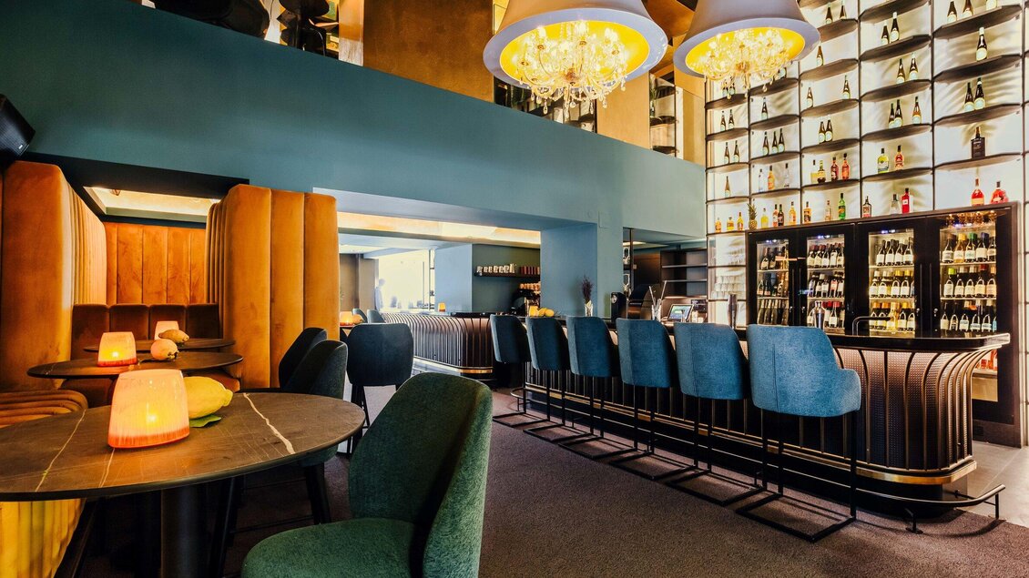 Eine stilvolle Bar mit modernen Sitzen und einer beleuchteten Getränkewand. Sanfte Beleuchtung schafft eine gemütliche Atmosphäre. | © Bar Amouro - Simon Bauer