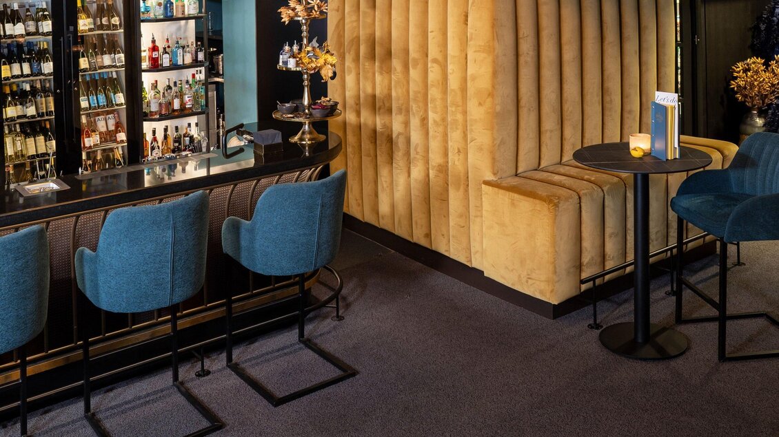 Eine stilvolle Bar mit blauen Stühlen und einer eleganten Theke. Im Hintergrund sind Regale mit verschiedenen Getränken zu sehen. | © Bar Amouro - Lucija Novak