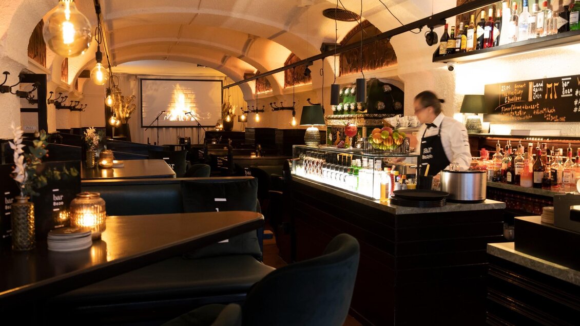 Ein stilvolles Restaurant mit warmem Licht und einer einladenden Atmosphäre. Im Hintergrund ist eine Bar mit einer Auswahl an Getränken und einem Mitarbeiter zu sehen. | © Magdalena Bereznicka