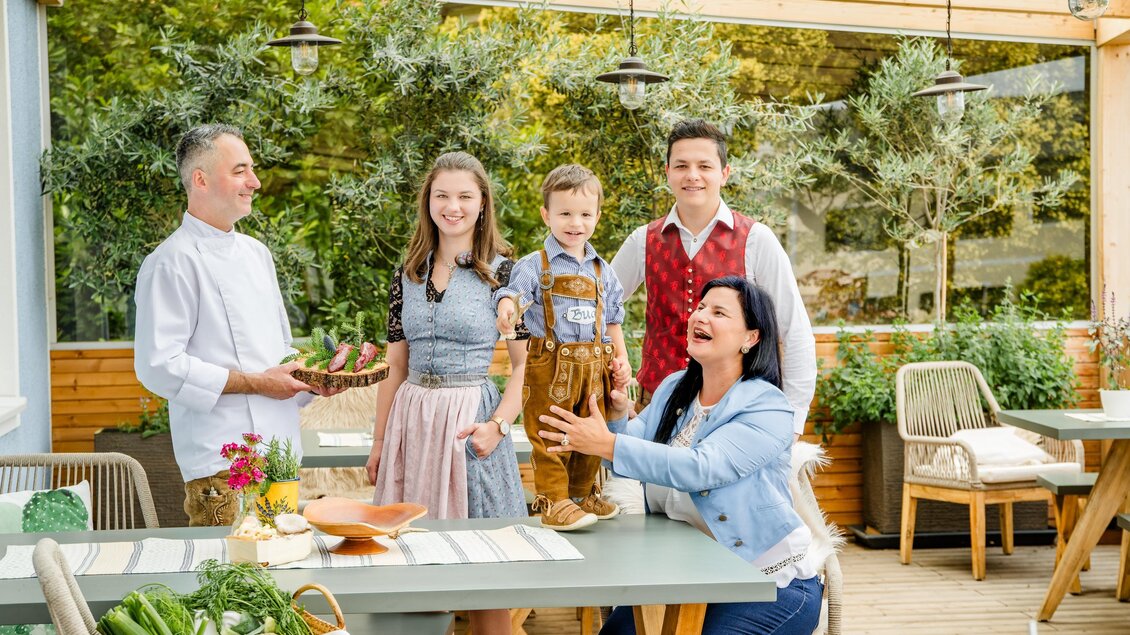 Eine fröhliche Familie steht in einem hellen, modernen Restaurant. Sie lächeln und genießen die Zeit miteinander. | © Region Graz, Mias Photoart