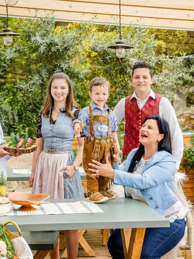 Eine fröhliche Familie steht in einem hellen, modernen Restaurant. Sie lächeln und genießen die Zeit miteinander. | © Region Graz, Mias Photoart