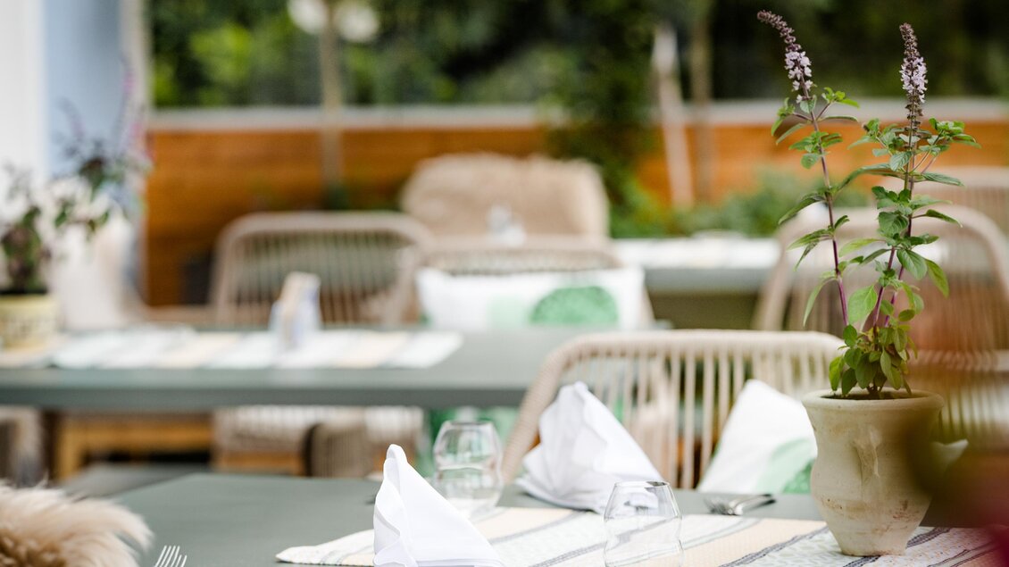 Ein einladendes Restaurant-Setting mit gedeckten Tischen und dekorativen Pflanzen. Die Atmosphäre ist freundlich und gemütlich, ideal für ein entspanntes Essen. | © Steiermark Tourismus - STG