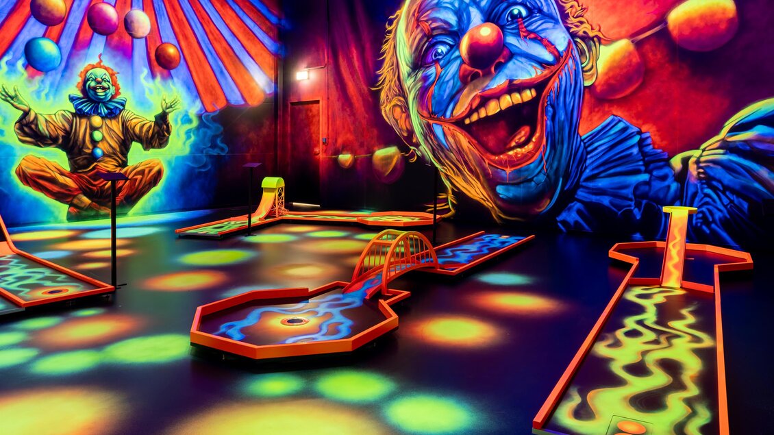 Indoor-Minigolfbahn mit bunten Neonfarben, 3D-Effekten und großflächigen Clown-Graffitis im Blacklight-Design | © Battlekart Gössendorf - Stefan Novotny
