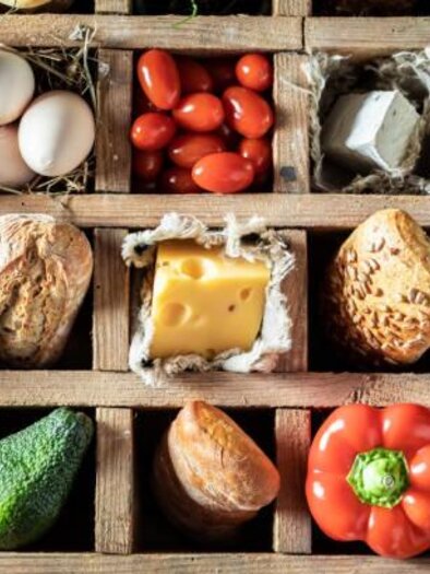 A wooden box with various fresh foods such as vegetables, eggs, and cheese. A colorful variety of reds, greens, and browns. | © Symbolfoto Pixabay