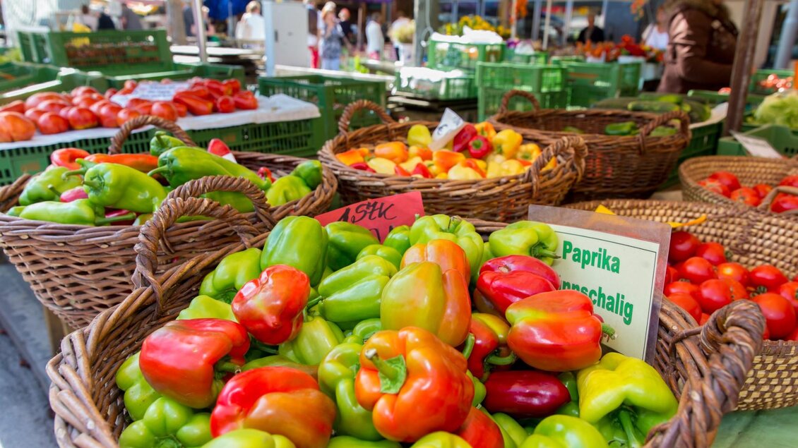 Körbe voller roter, grüner und gelber Paprika sowie Tomaten auf einem Marktstand | © Graz Tourismus - Harry Schiffer