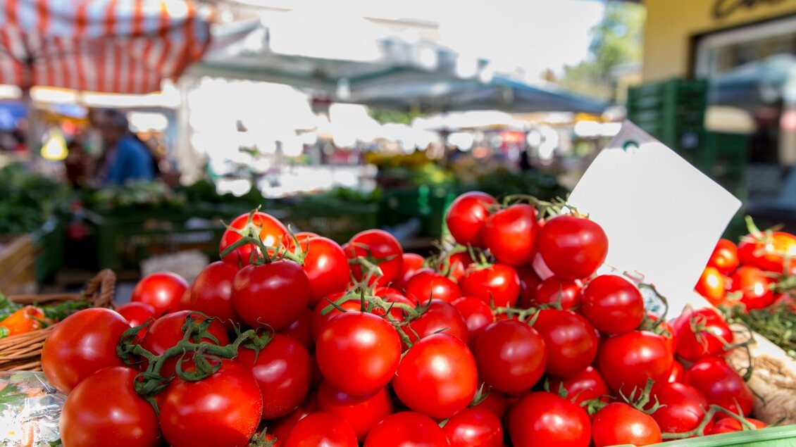 Grüne Kiste voller leuchtend roter Tomaten mit Stielen auf einem Marktstand | © Graz Tourismus - Harry Schiffer