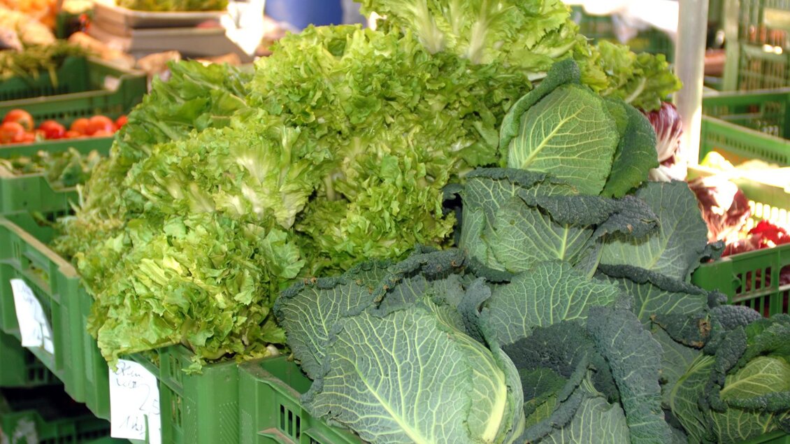 Grüner Salat und Kohlköpfe liegen in grünen Kisten auf einem Marktstand | © Graz Tourismus - icegirl