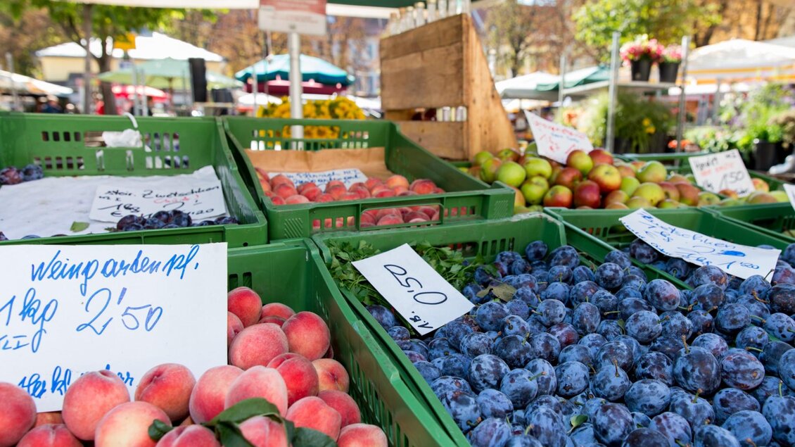 Grüne Kisten mit Pfirsichen, Zwetschken und Äpfeln unter einem gestreiften Sonnenschirm | © Graz Tourismus - Harry Schiffer
