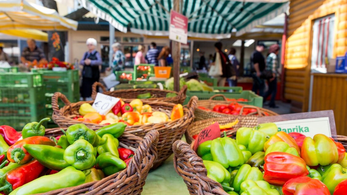 Körbe mit roten, grünen und gelben Paprika auf einem Marktstand, im Hintergrund Marktbesucher | © Graz Tourismus - Harry Schiffer