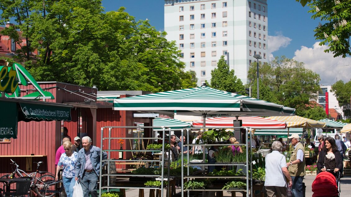 Menschen schlendern zwischen Marktständen mit Pflanzen und Gemüseschalen unter Sonnenschirmen | © Graz Tourismus - Harry Schiffer