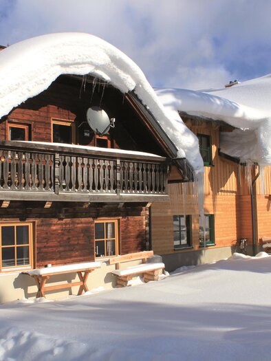 Ein charmantes Holzhaus im Winter, umgeben von Schnee. Das Dach ist dick mit Schnee bedeckt und es gibt eine schöne Aussicht auf die Berge. | © Erlebnisregion Murtal