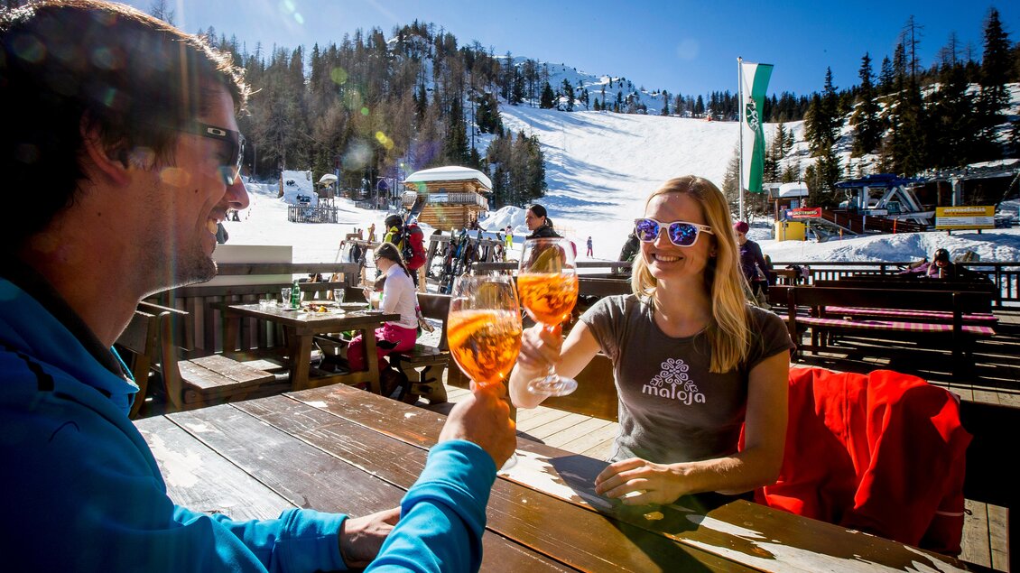 Ein sonniger Tag auf einer Skipiste mit fröhlichen Menschen. Zwei Personen stoßen mit Getränken an und genießen die alpine Atmosphäre. | © Berggasthof Bottinghaus