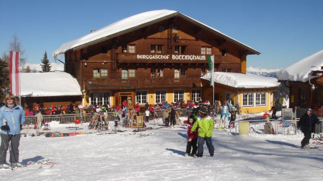 Ein gemütliches Berggasthaus im Schnee mit vielen Skifahrern und Urlaubern. Der Himmel ist klar und die Umgebung bietet eine wunderschöne Winterlandschaft. | © Berggasthof Bottinghaus