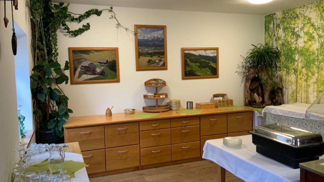 Ein gemütlicher Raum mit Holzschränken und Bildern von Landschaften an der Wand. Auf einem Tisch stehen Gläser und ein Buffetwagen. | © Berggasthof Jager GmbH