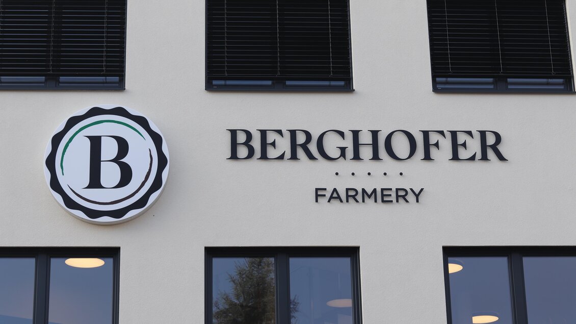 Ein modernes Gebäude mit der Aufschrift "Berghofer Farmery". Das Logo zeigt einen stilisierten Buchstaben "B" in einem runden Rahmen. | © Berghofer Farmery