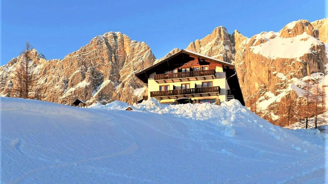 Ein schönes Chalet im Schnee, umgeben von beeindruckenden Bergen. Der Himmel ist klar und die Sonne scheint. | © Berghotel Türlwand