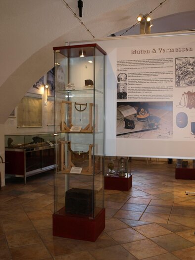 An exhibition space with display cases and historical artifacts. Informative panels with texts and images can be seen on the walls.