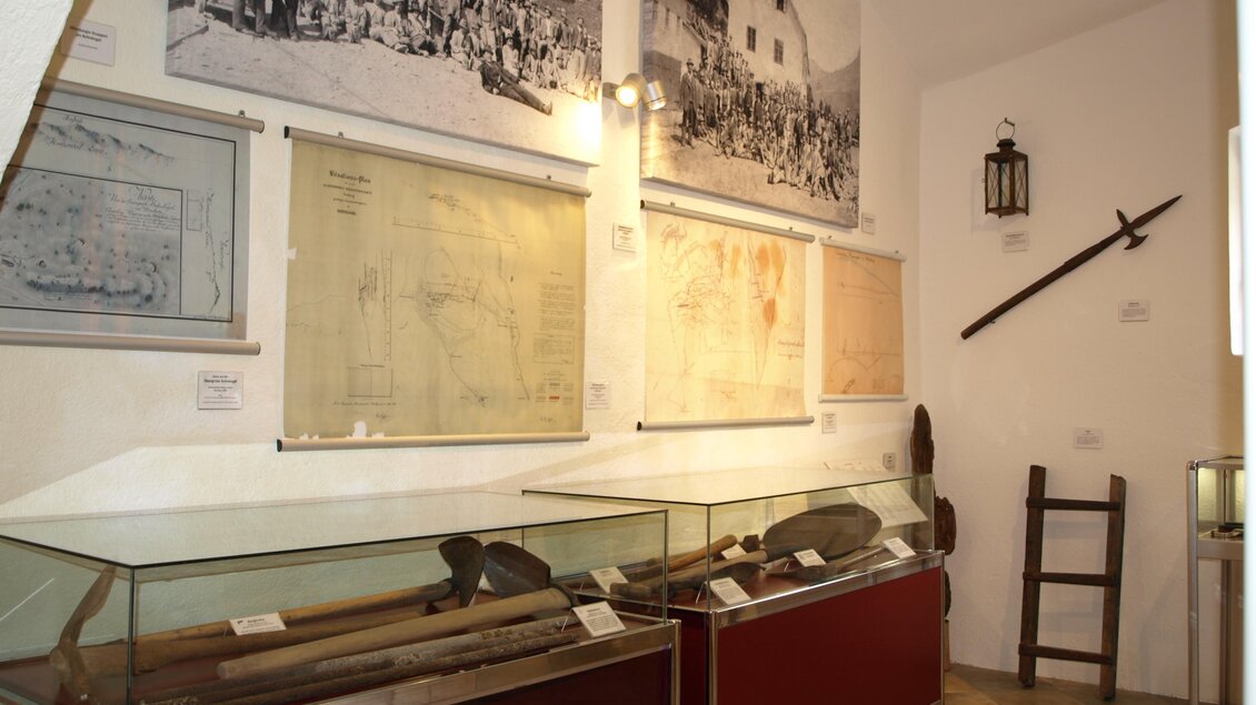 Ein Museum mit historischen Artefakten, darunter Waffen und Karten. An den Wänden hängen alte Fotografien und Dokumente.