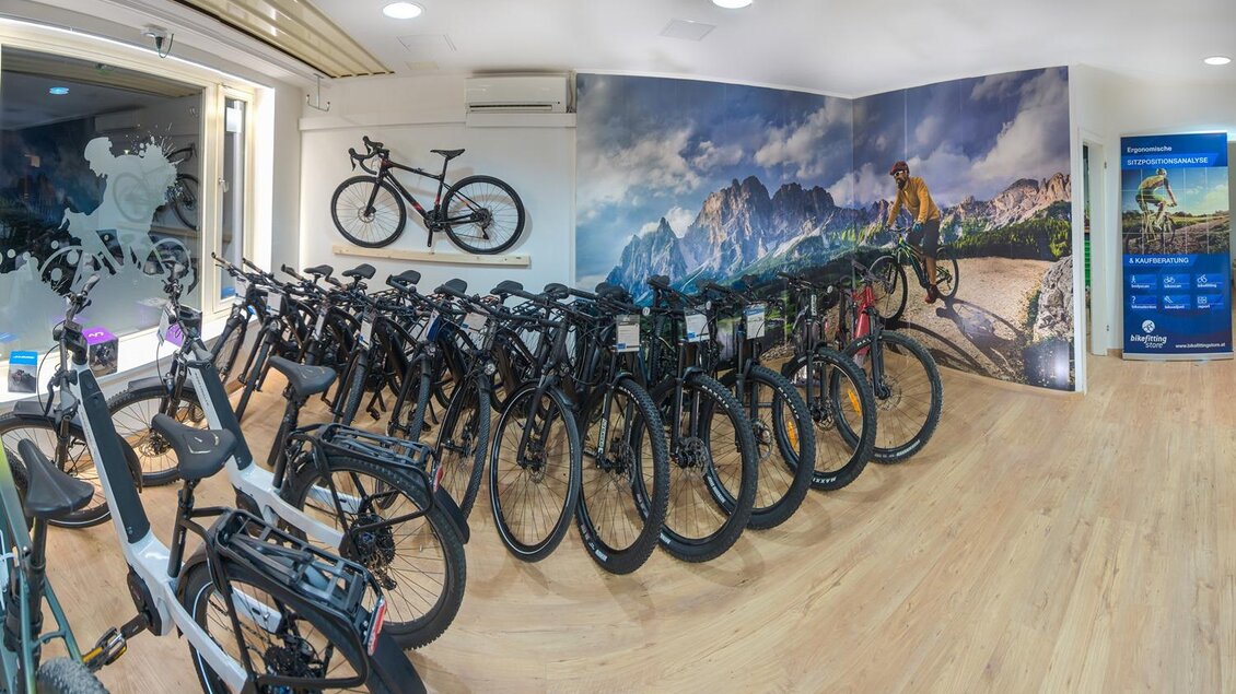 Ein moderner Fahrradladen mit vielen verschiedenen Fahrrädern. Im Hintergrund ist eine große Wand mit einer Berglandschaft zu sehen. | © Bikefitting Store_Hiebler