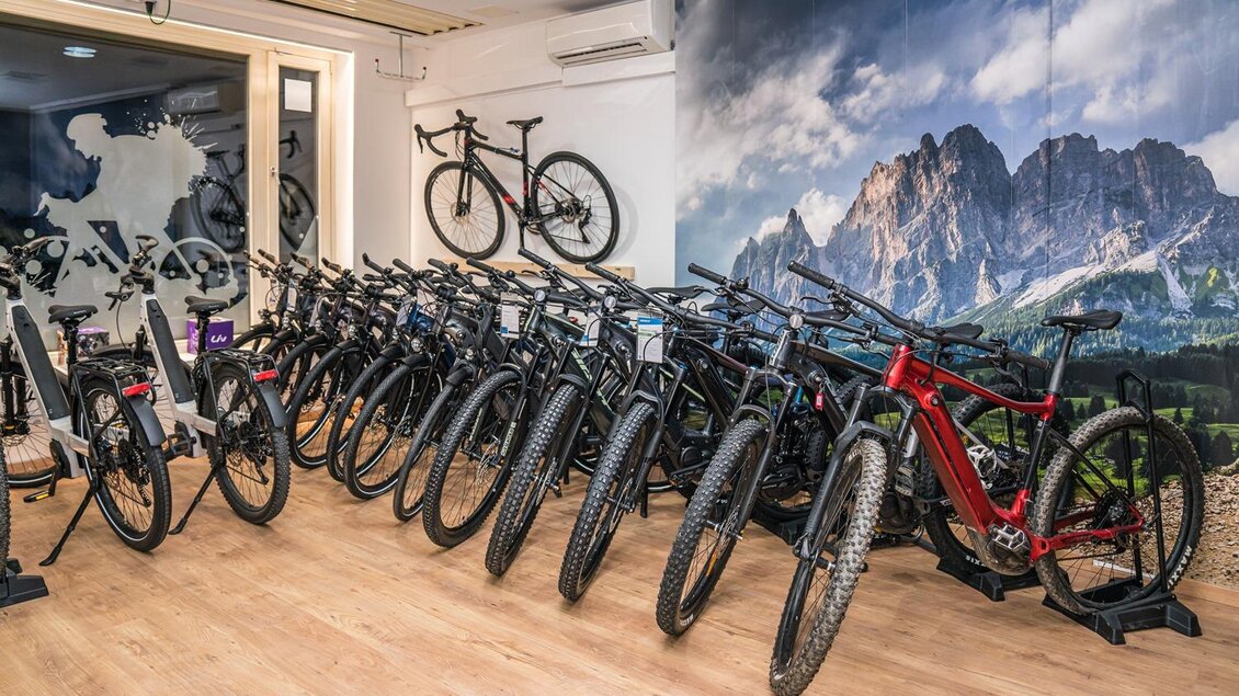 Ein Fahrradgeschäft mit mehreren Mountainbikes in einer eleganten Ausstellung. Im Hintergrund ist ein Wandbild mit Berglandschaft zu sehen. | © Bikefitting Store_Hiebler
