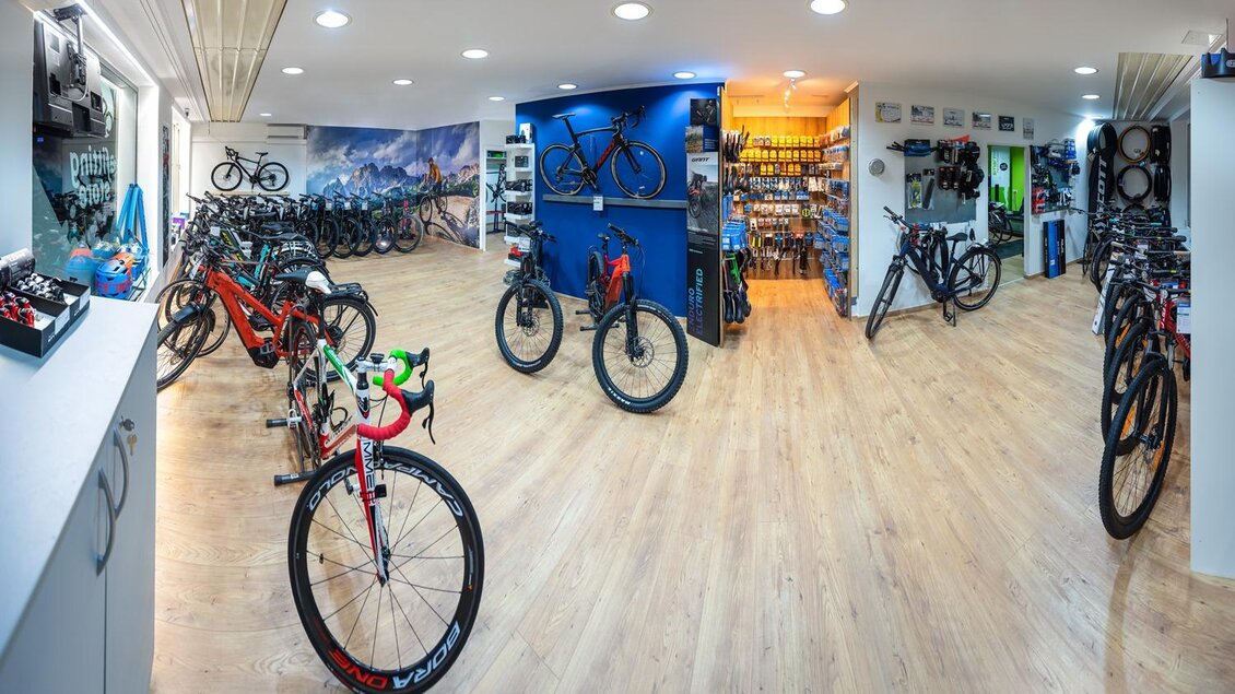Ein Fahrradgeschäft mit vielen Fahrrädern und hellem Holzfußboden. Die Wände sind mit Fahrradzubehör und -teilen dekoriert. | © Bikefitting Store_Hiebler