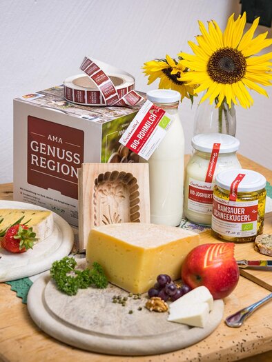 Ein schöner Tisch mit verschiedenen Käsesorten, frischem Obst und Gemüse. Im Hintergrund stehen Milchprodukte und eine Sonnenblume. | © Netzwerk Kulinarik wildbild