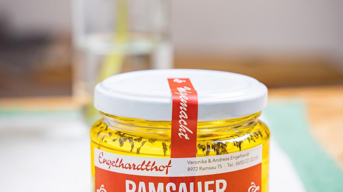 Ein Glas Ramsauer Schneekugerl steht auf einem Tisch. Im Hintergrund ist eine Vase mit Sonnenblumen zu sehen. | © Netzwerk Kulinarik wildbild