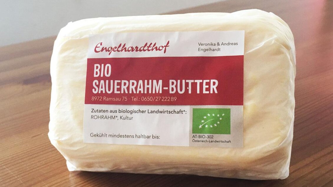 Ein Stück Bio Sauerrahm-Butter in einer Verpackung. Die Verpackung hat ein rotes Label mit Informationen über die Herkunft und die Bio-Zertifizierung. | © Engelhardthof