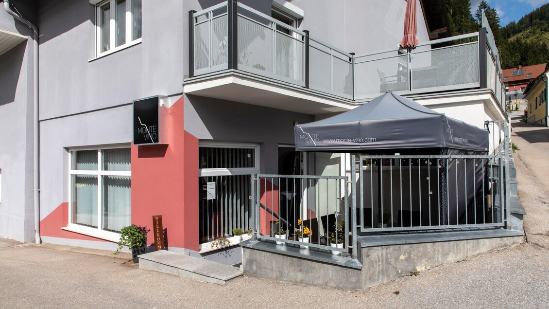 Ein modernes Gebäude mit einem grauen und roten Außenanstrich. Vor dem Eingang steht ein Pavillon und es gibt einen kleinen draußen Bereich. | © TV Region Graz - Lunghammer