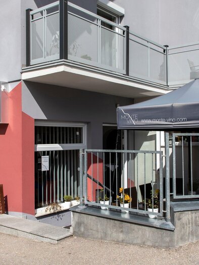 Ein modernes Gebäude mit einem grauen und roten Außenanstrich. Vor dem Eingang steht ein Pavillon und es gibt einen kleinen draußen Bereich. | © TV Region Graz - Lunghammer