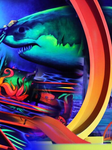 A colorful indoor mini-golf game featuring vibrant art and two cheerful children. The image captures the exciting and imaginative atmosphere of the game. | © Sieglinde Wrabl