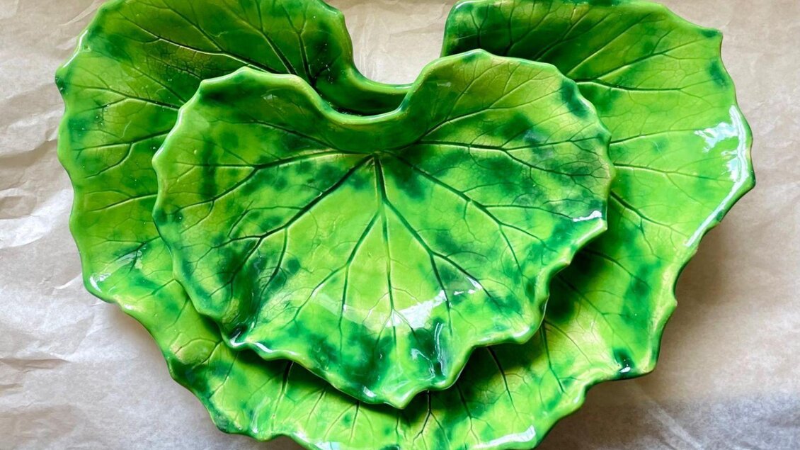 Zwei grüne Servierplatten in Form von Blättern. Die Platten haben ein glänzendes Finish und sind detailliert gestaltet. | © Blattwerk Manufaktur, Theresa Stieböck