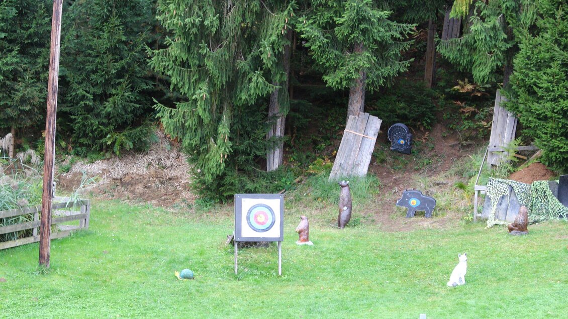 Ein Zielscheibe in einem grünen Bereich, umgeben von Bäumen. Im Hintergrund sind einige dekorative Figuren und Objekte zu sehen. | © Archery Freaks - Frahs