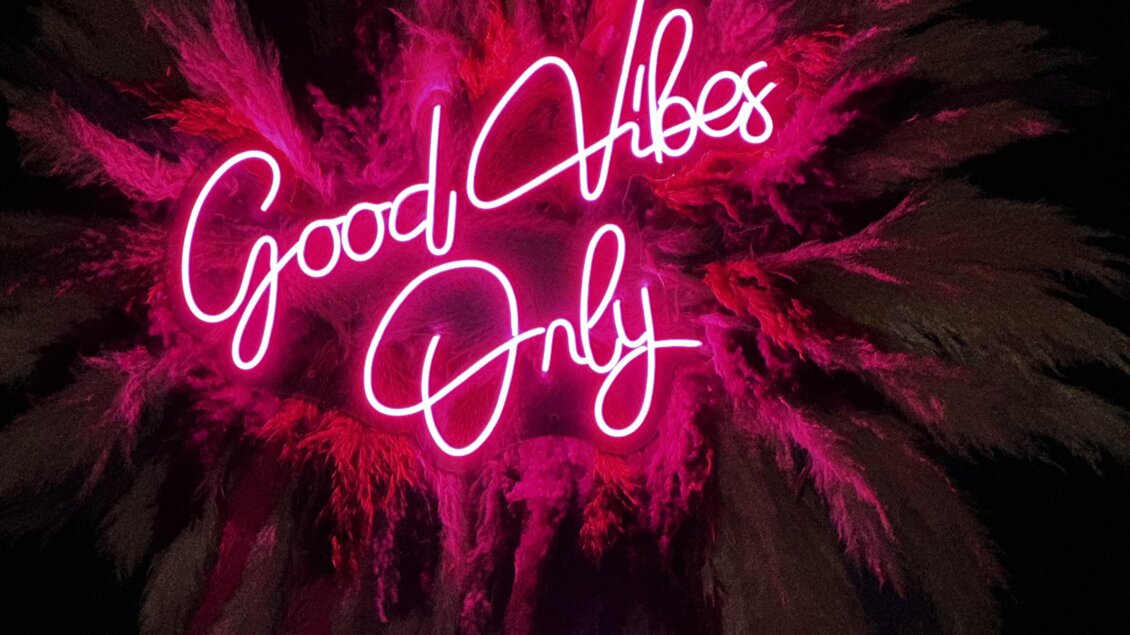 Ein leuchtendes neones Schild mit der Aufschrift "Good Vibes Only". Der Hintergrund ist in lebhaften Farben gestaltet, die eine fröhliche Stimmung vermitteln. | © Bonbon