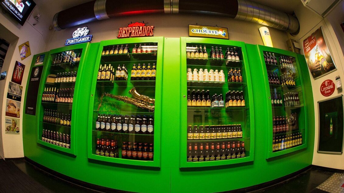 Eine große grüne Wand mit Kühlschränken, die viele Flaschen verschiedene Getränke zeigen. Die Umgebung ist modern und einladend. | © Brot & Spiele