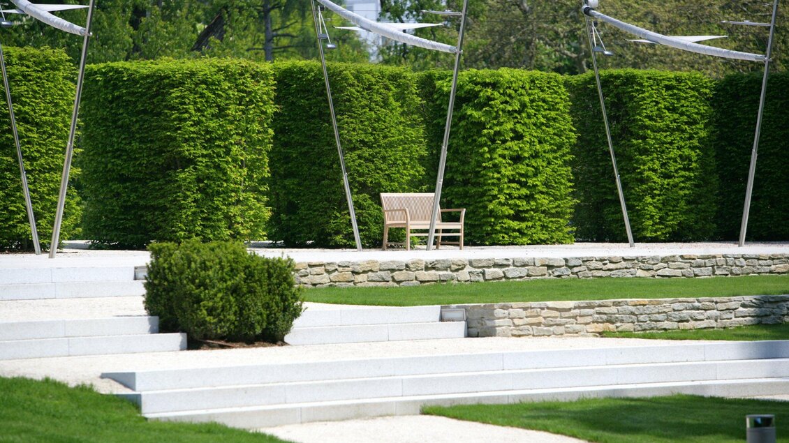 Holzbank vor geschnittenen Hecken und Steinmauer im Burggarten Graz | © Graz Tourismus-Harry Schiffer
