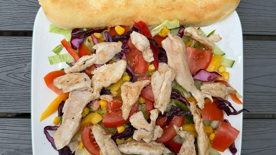 Ein frischer Salat mit Gemüse und gebratenem Hähnchenfleisch. Dazu ein knuspriges Brot. | © Kevin Sönmez