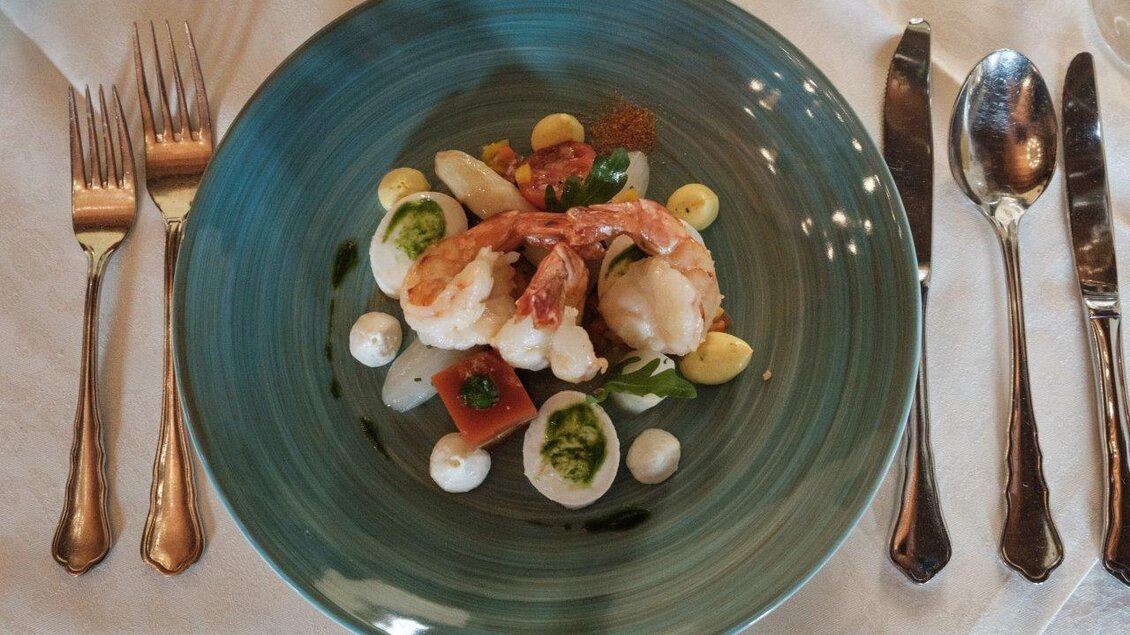 Ein elegantes Gericht mit Garnelen, frischem Gemüse und Saucen auf einem stilvollen Teller. Die ansprechende Präsentation lädt zum Genießen ein. | © Schilcherland Steiermark