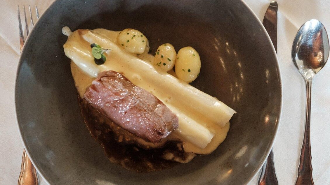 Ein Teller mit gegrilltem Fleisch, weißen Spargeln und kleinen Kartoffeln. Das Gericht ist schön angerichtet und serviert. | © Schilcherland Steiermark